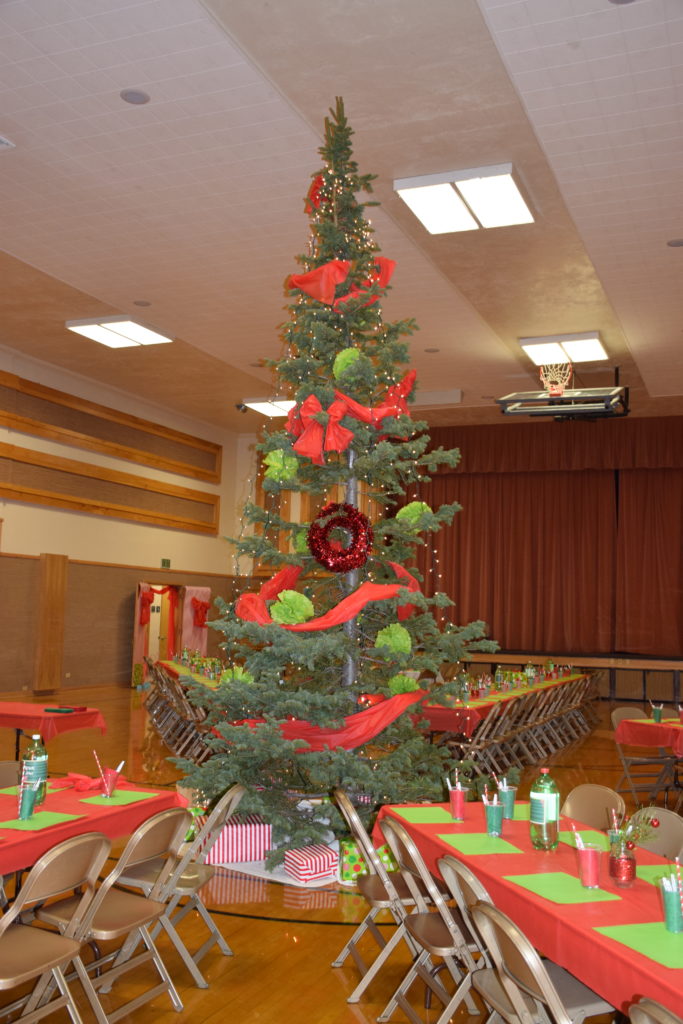 Giant Christmas tree decorated with red and green in the middle of rows of tables