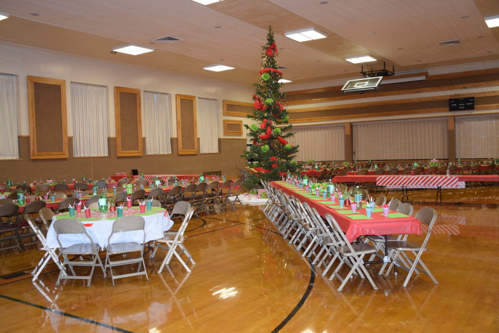 Giant Christmas tree decorated with red and green in the middle of rows of tables