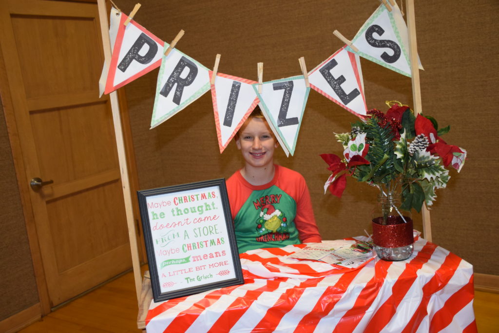 Kid sitting at table with prizes banner