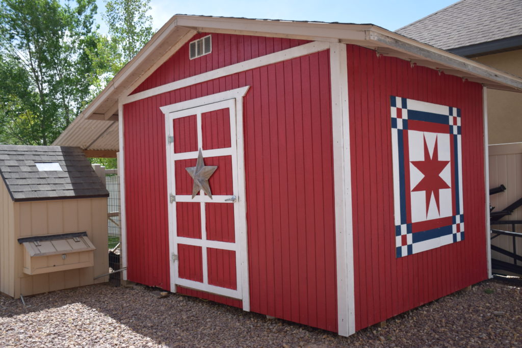 Red shed with white trim and barn quilt on the side