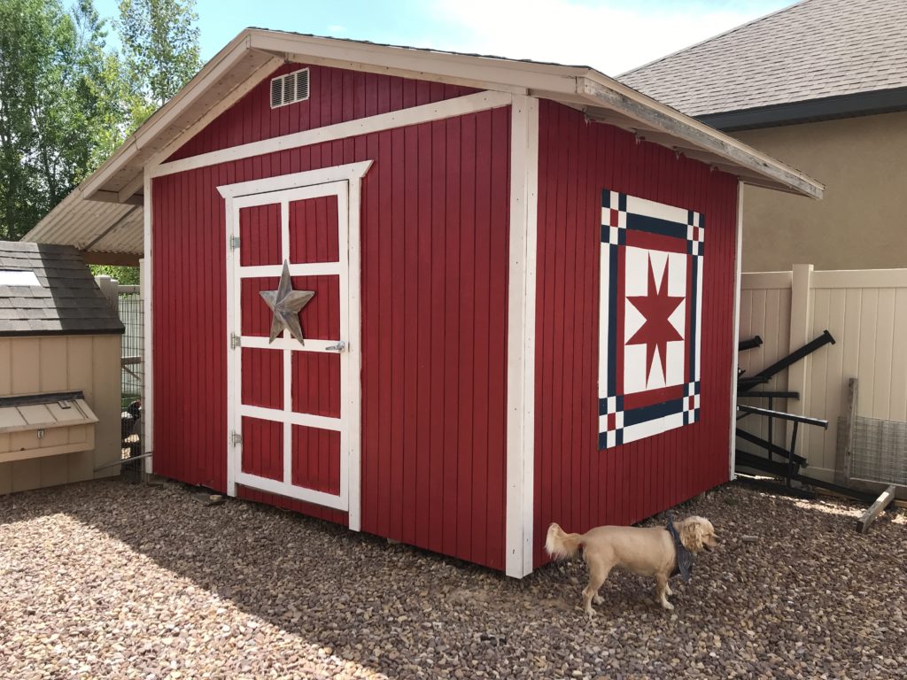 Red shed with white trim and barn quilt on the side