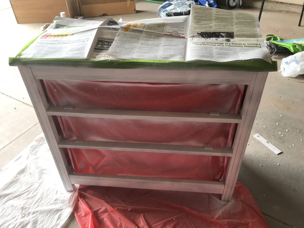 Dresser with newspaper taped to top and sides sprayed with chalk paint