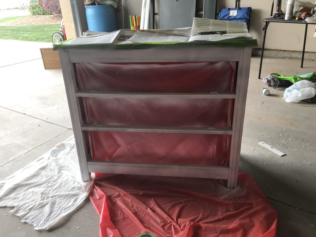 Dresser with newspaper taped to top and sides sprayed with chalk paint