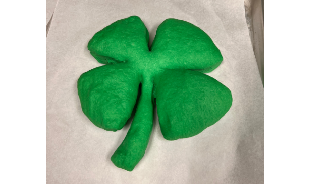 Green bread shaped like a shamrock ready to be proofed and baked