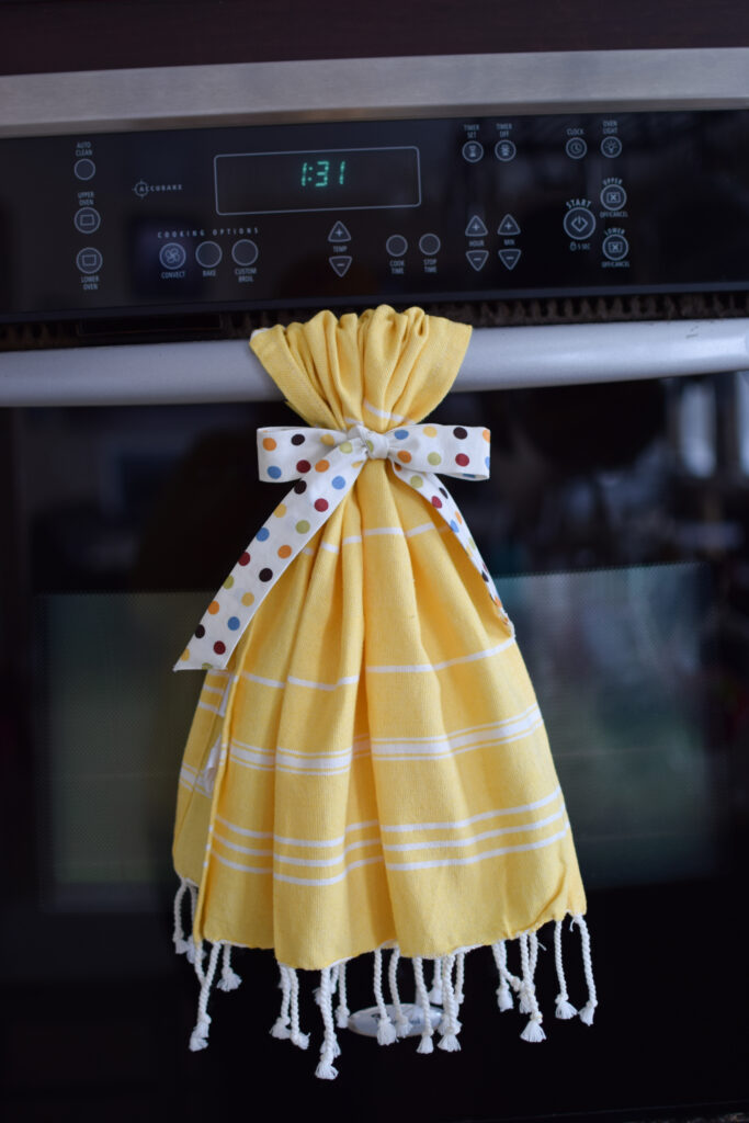 Yellow hand towel with polka dot fabric ribbon tied to the oven handle