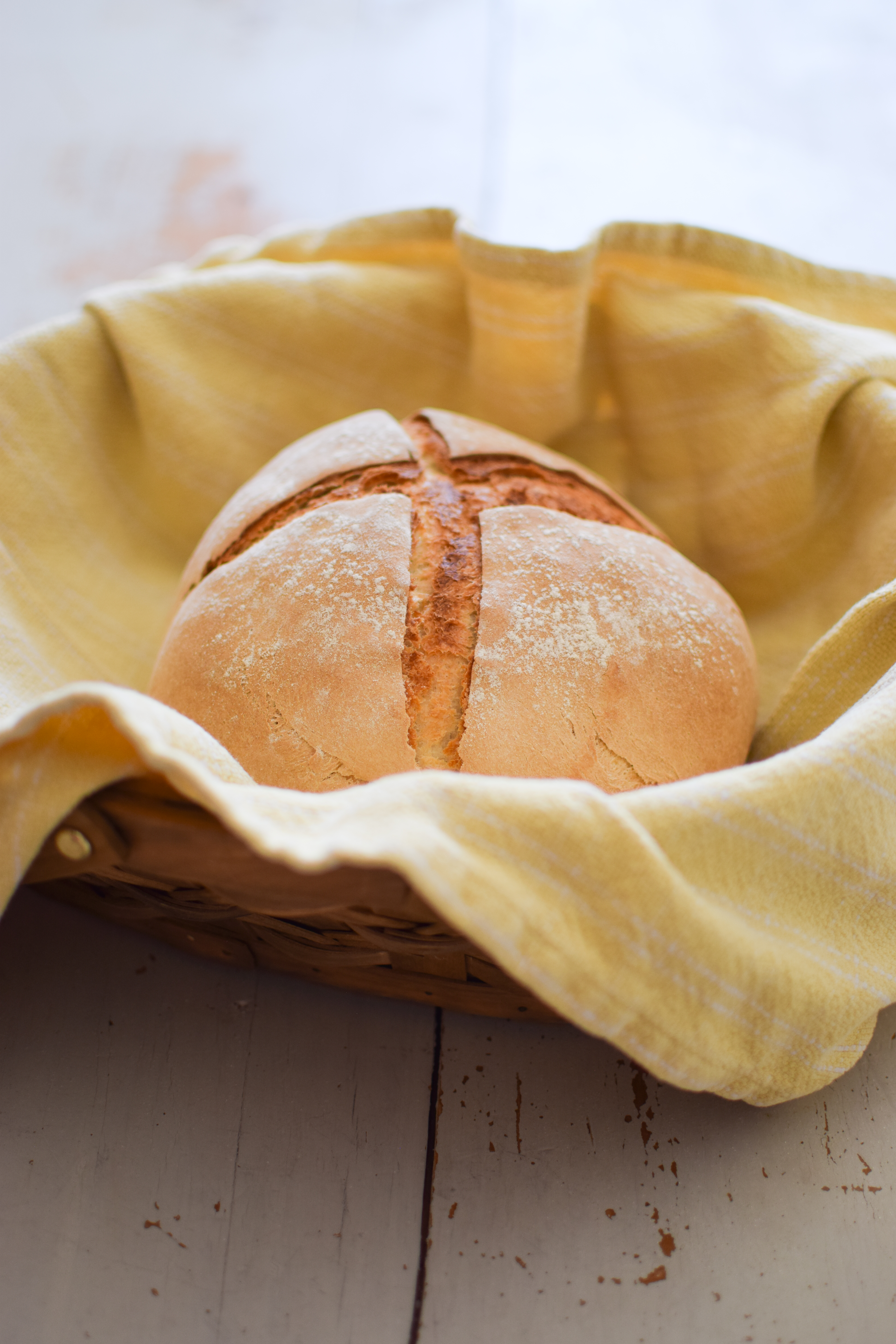 Sourdough boule in basket with yellow cloth