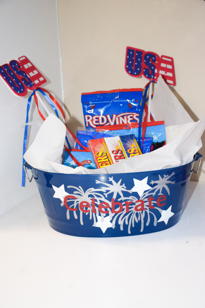 Blue bucket with vinyl stars, fireworks and word celebrate. Bucket is filled with sparklers, candy and banners