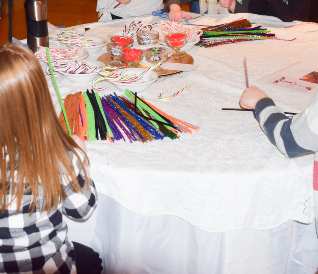 Table with candy canes, googly eyes, red pom poms and pipe cleaners on it